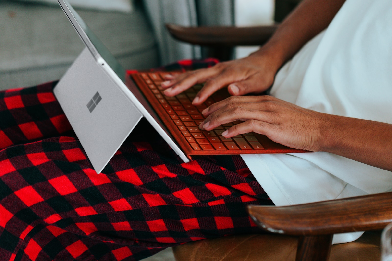 Person in checkered pajamas on their Surface laptop at home